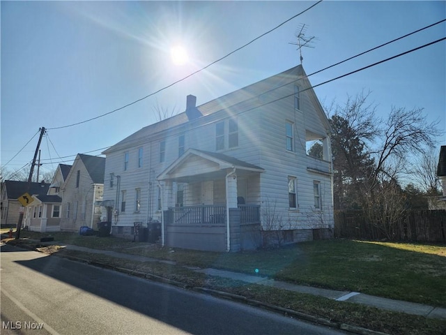 view of front facade featuring a porch, a front lawn, and fence