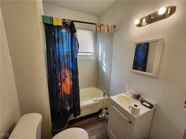 full bathroom featuring vanity, wood finished floors, shower / bath combo with shower curtain, toilet, and a textured wall