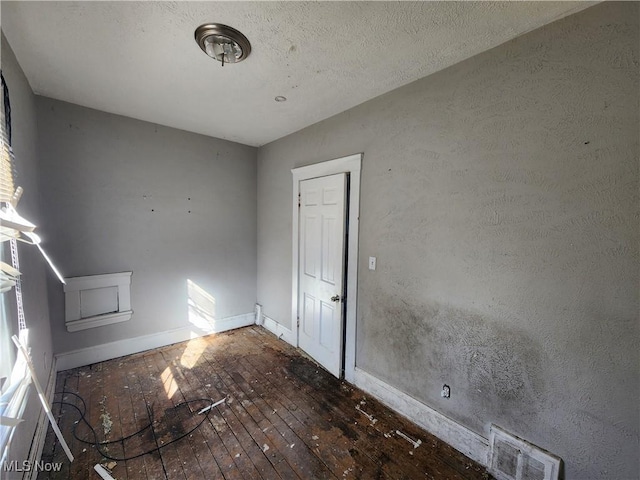 unfurnished room featuring visible vents, baseboards, and hardwood / wood-style floors