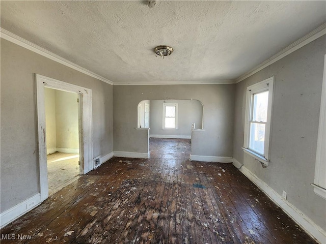 empty room with hardwood / wood-style floors, crown molding, baseboards, and arched walkways