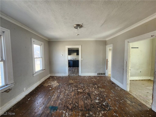 unfurnished room with visible vents, crown molding, baseboards, hardwood / wood-style floors, and a textured ceiling