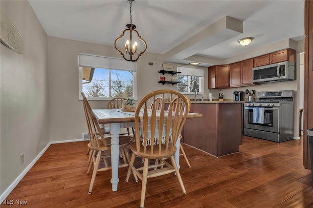 dining space with a notable chandelier, plenty of natural light, baseboards, and wood finished floors