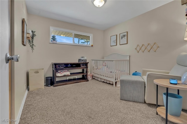 carpeted bedroom featuring baseboards and a crib