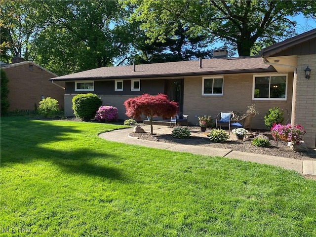 back of property featuring brick siding, a lawn, and a chimney