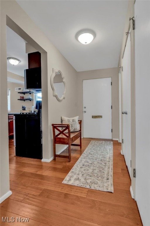 hall with baseboards and light wood-style flooring