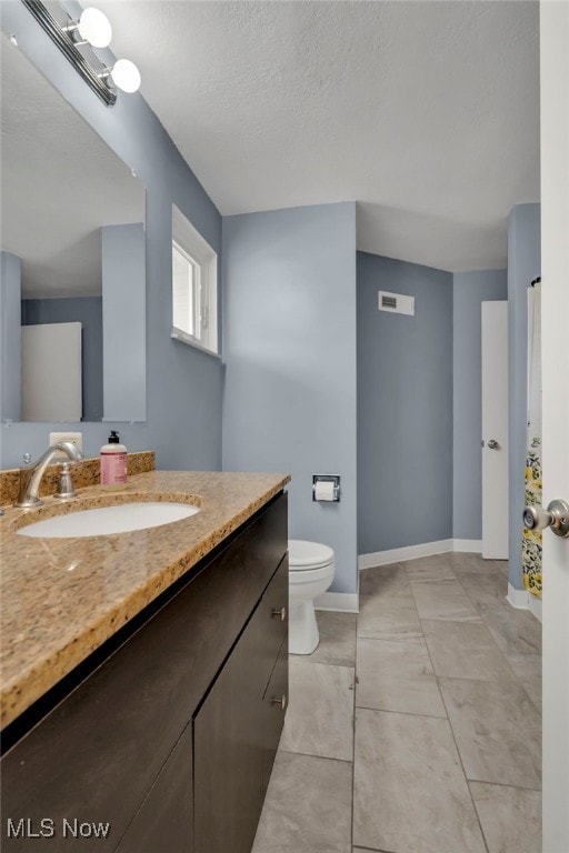 bathroom with visible vents, toilet, a textured ceiling, baseboards, and vanity