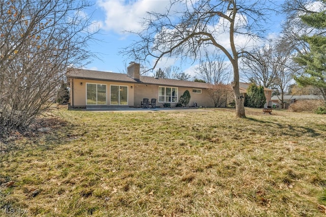 rear view of house with a patio area, a lawn, and a chimney