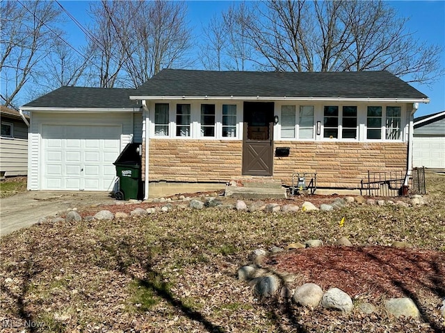 ranch-style house with concrete driveway, an attached garage, stone siding, and roof with shingles