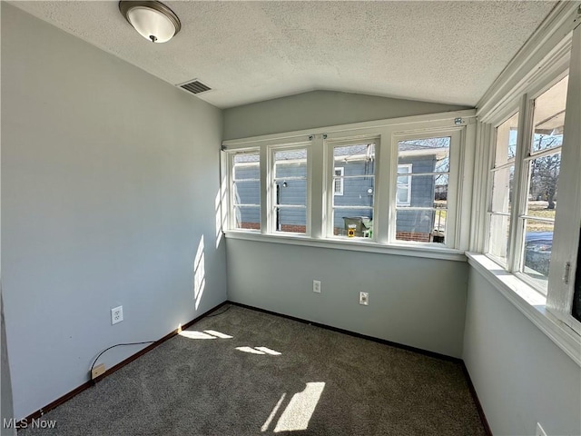 carpeted spare room featuring baseboards, visible vents, a textured ceiling, and lofted ceiling