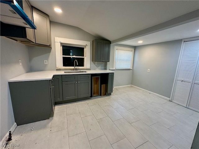 kitchen with a sink, baseboards, lofted ceiling, and light countertops