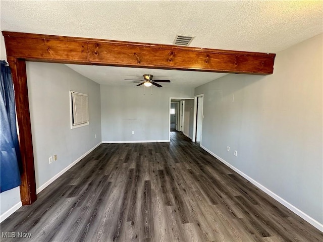 empty room with visible vents, beamed ceiling, a textured ceiling, baseboards, and dark wood-style flooring