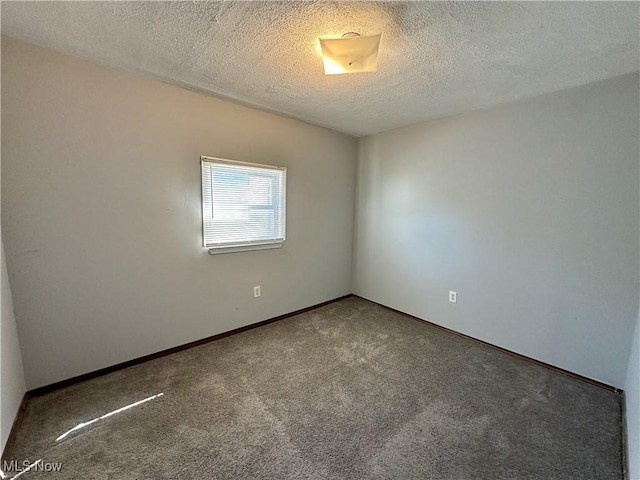 carpeted spare room with baseboards and a textured ceiling