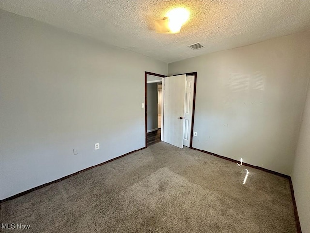 carpeted spare room featuring baseboards, visible vents, and a textured ceiling