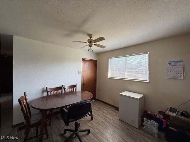 dining area featuring ceiling fan, light wood-type flooring, and a textured ceiling