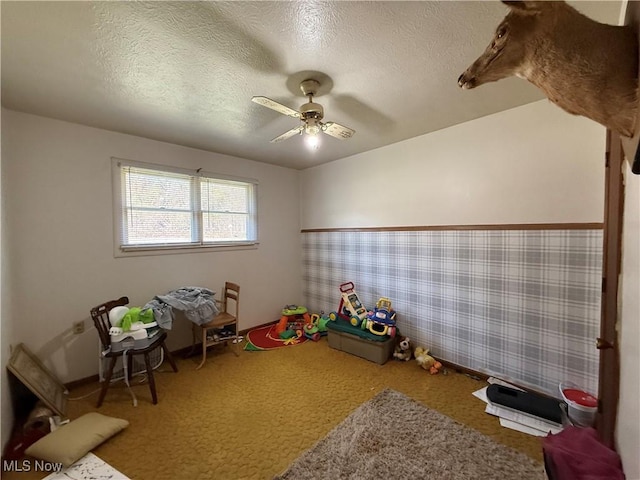 rec room featuring ceiling fan, carpet, wallpapered walls, and a textured ceiling