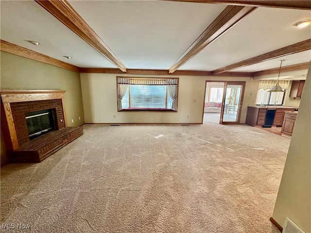 unfurnished living room with baseboards, beam ceiling, light carpet, and a fireplace