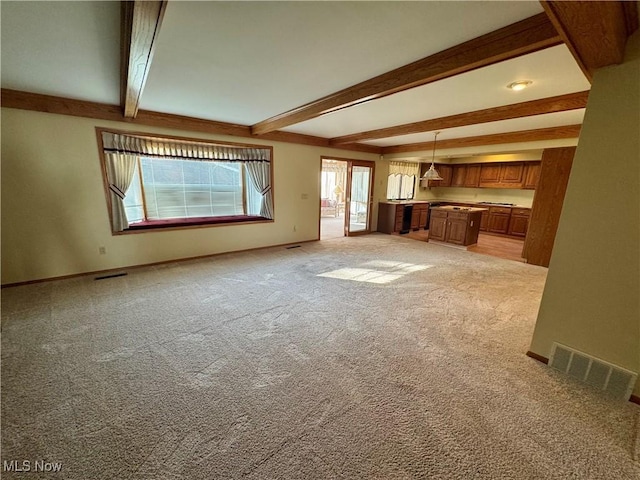 unfurnished living room featuring baseboards, visible vents, beam ceiling, and light carpet