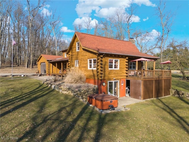 back of house with a yard, a wooden deck, log siding, a chimney, and a hot tub