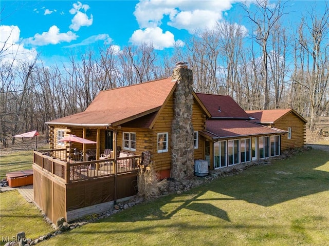 rear view of house with a deck, log exterior, a chimney, and a yard