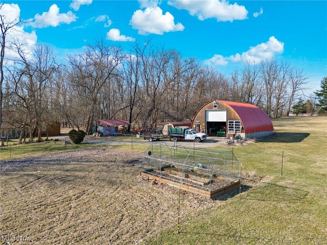 view of yard featuring a detached garage, an outbuilding, and a vegetable garden