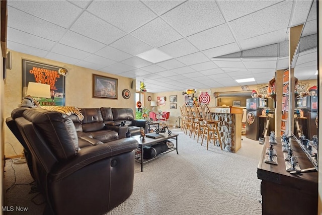 carpeted living area featuring a dry bar and a drop ceiling