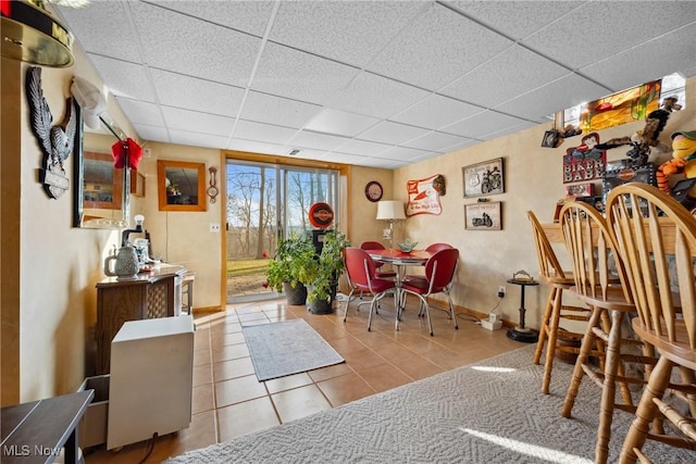 tiled dining room featuring a drop ceiling and baseboards