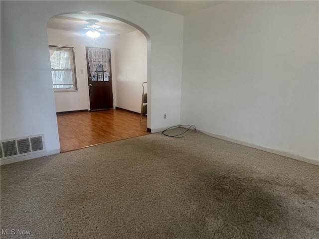 empty room with visible vents, arched walkways, and carpet