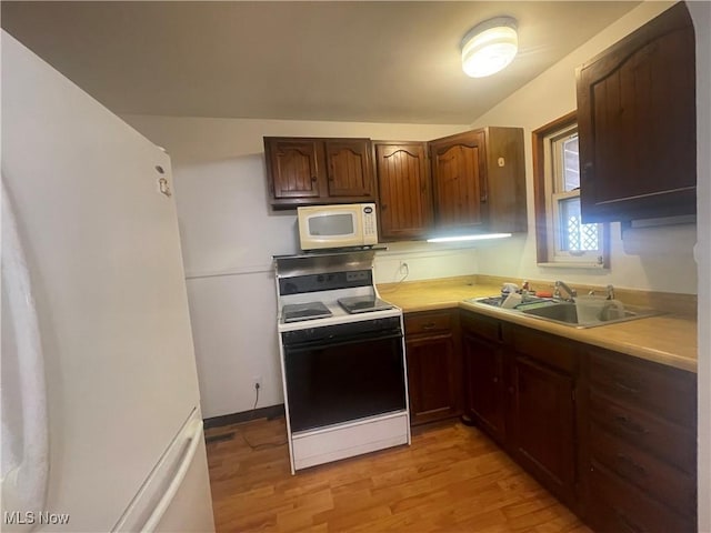 kitchen featuring white appliances, light wood-style flooring, light countertops, and a sink