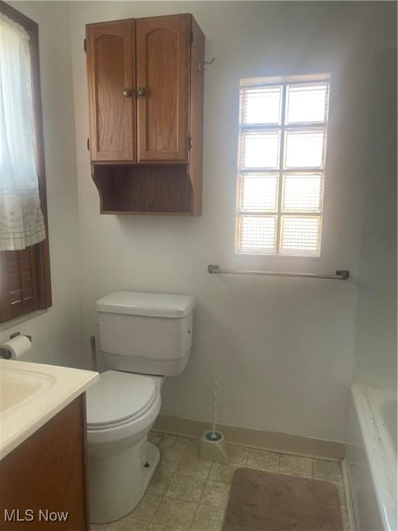 full bath featuring a tub, toilet, vanity, and baseboards