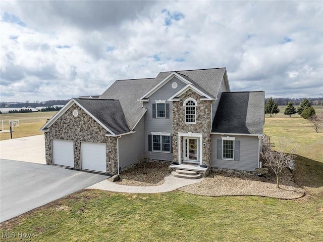 traditional-style house featuring a front lawn, an attached garage, stone siding, and driveway