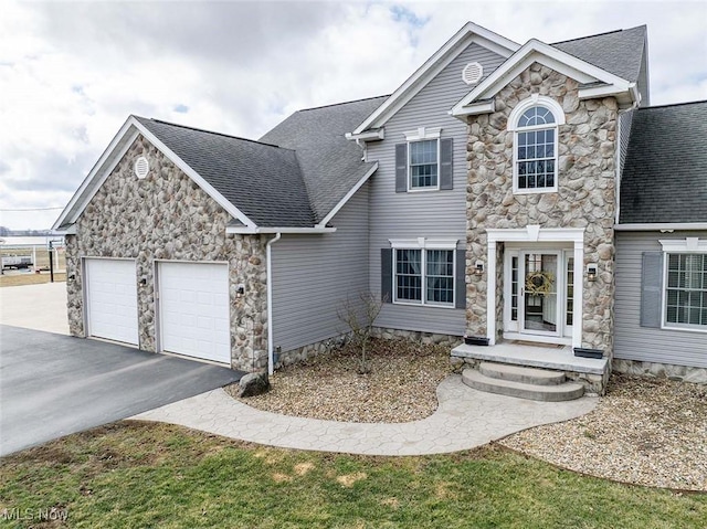 view of front of house featuring driveway, an attached garage, and a shingled roof