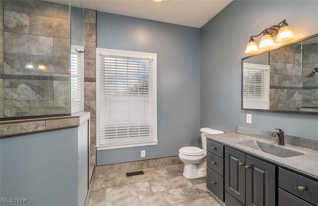 bathroom featuring vanity, toilet, a walk in shower, and visible vents