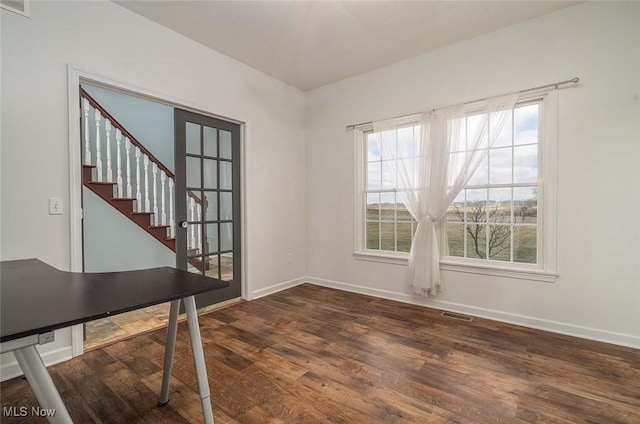 unfurnished office with dark wood-type flooring, baseboards, and visible vents