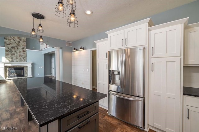 kitchen featuring visible vents, stainless steel fridge with ice dispenser, a fireplace, white cabinets, and ornate columns