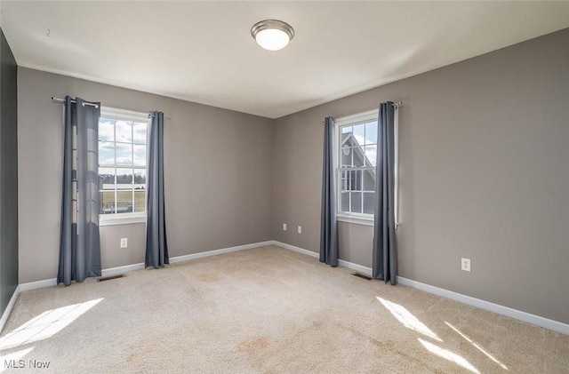 unfurnished room featuring visible vents, plenty of natural light, baseboards, and carpet