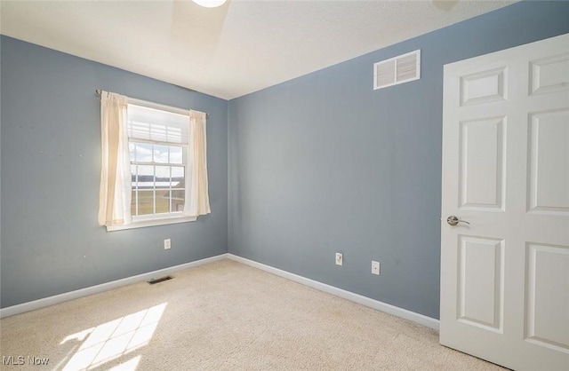 carpeted empty room featuring visible vents and baseboards