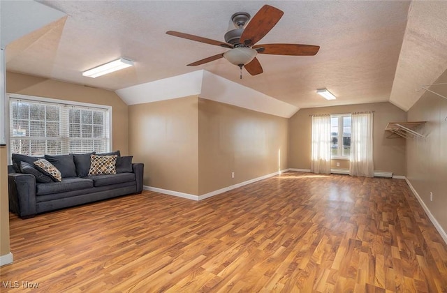 unfurnished living room featuring a textured ceiling, wood finished floors, and vaulted ceiling