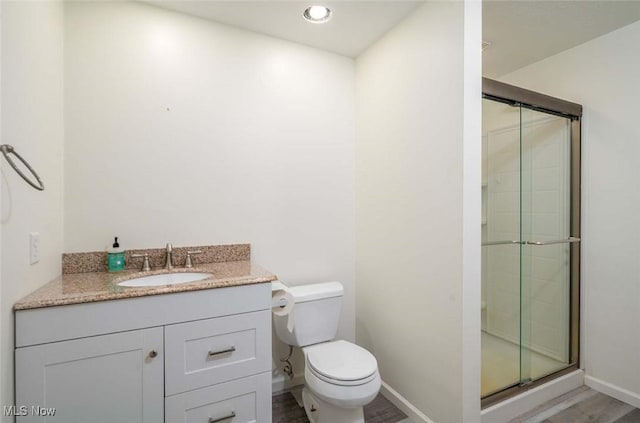 full bath with vanity, wood finished floors, baseboards, a stall shower, and toilet