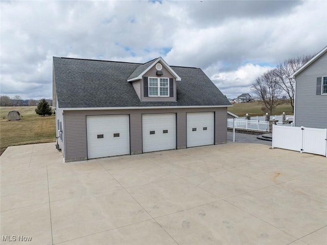 garage featuring concrete driveway and fence