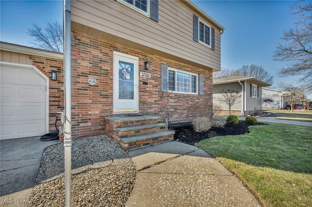 entrance to property featuring brick siding, a yard, and a garage