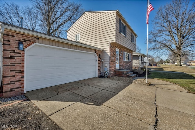 view of side of home featuring a garage, brick siding, and driveway