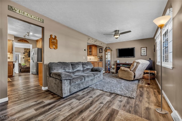 living room with dark wood finished floors, baseboards, a textured ceiling, and a ceiling fan