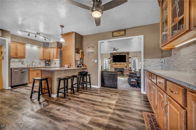 kitchen featuring dishwasher, dark wood finished floors, a kitchen bar, and a sink