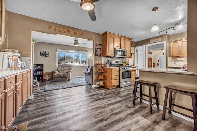 kitchen featuring a textured ceiling, dark wood-style flooring, a kitchen bar, and stainless steel appliances