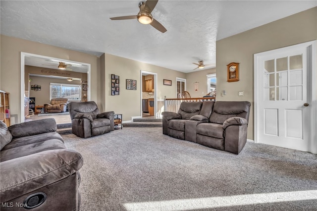 carpeted living room with a textured ceiling, baseboards, and a ceiling fan