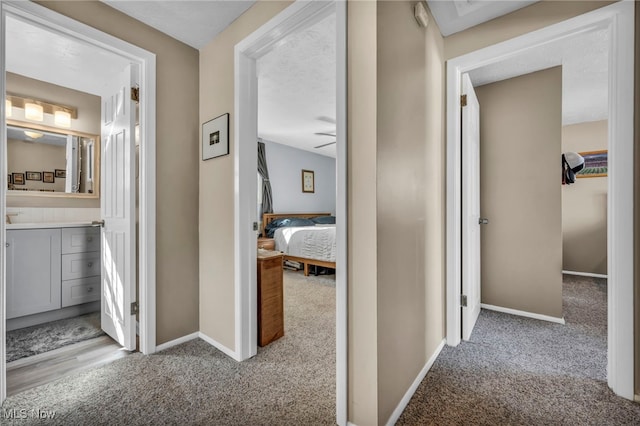 hall with baseboards and light colored carpet