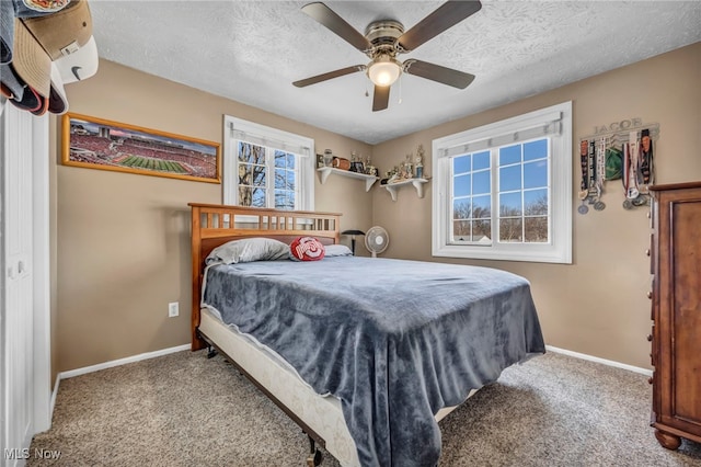 carpeted bedroom featuring baseboards, a textured ceiling, and a ceiling fan