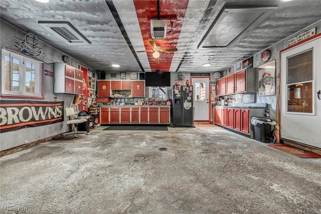 garage featuring visible vents and black fridge