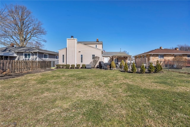 back of house with a yard, a fenced backyard, and a chimney