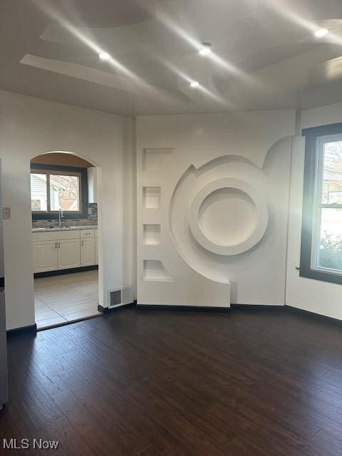 unfurnished room with visible vents, a sink, and dark wood-style flooring